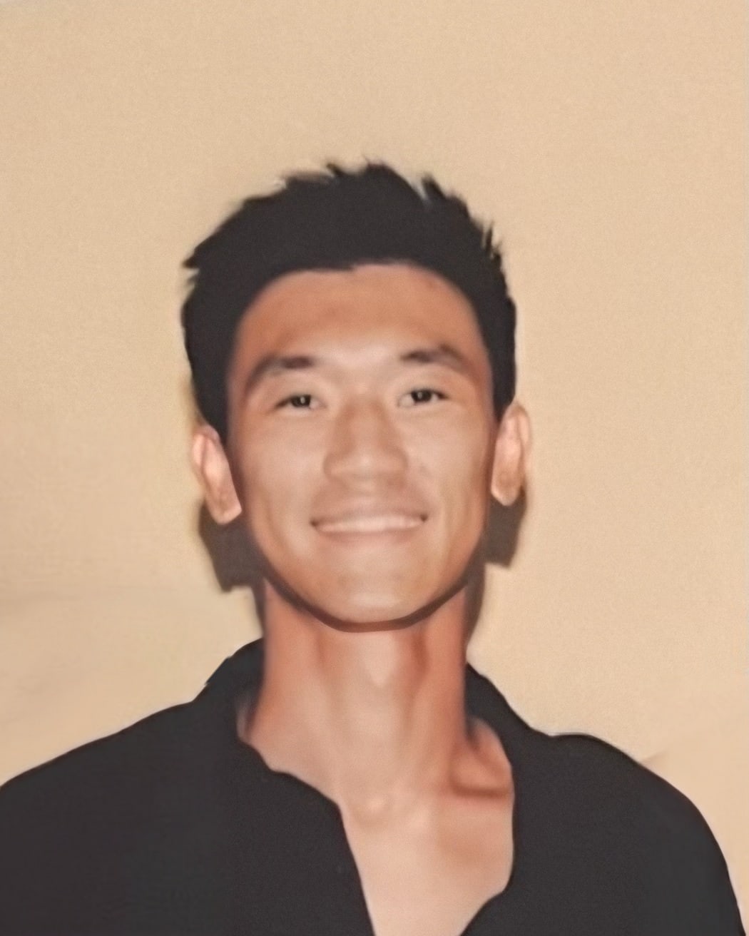 Photo of Sherman Lau, the founder, smiling, in a black shirt against a warm wall